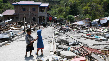 5bb5b793b3bc4-dua-anak-bermain-di-antara-reruntuhan-bangunan-yang-rusak-akibat-gempa-7-4-pada_375_211